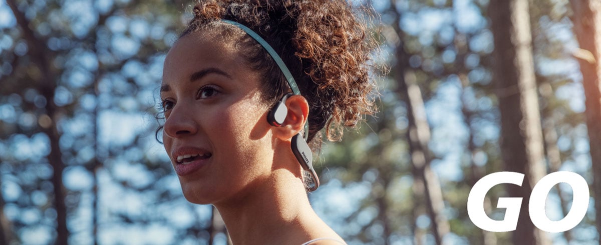 Zdjęcie ze zbliżeniem na kobietę noszącą słuchawki sportowe z przewodzeniem kostnym