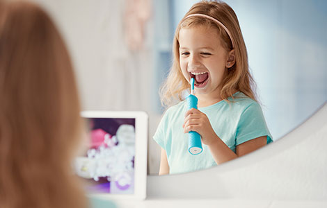 Dziewczynka myjąca zęby szczoteczką soniczną dla dzieci Philips Sonicare for Kids.