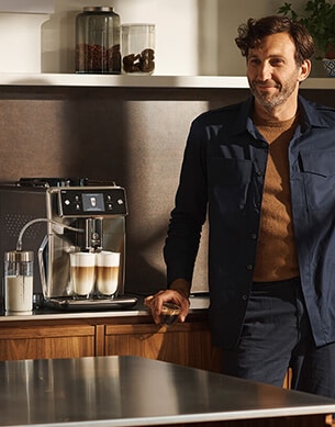 Mężczyzna stojący w kuchni obok ekspresu do kawy