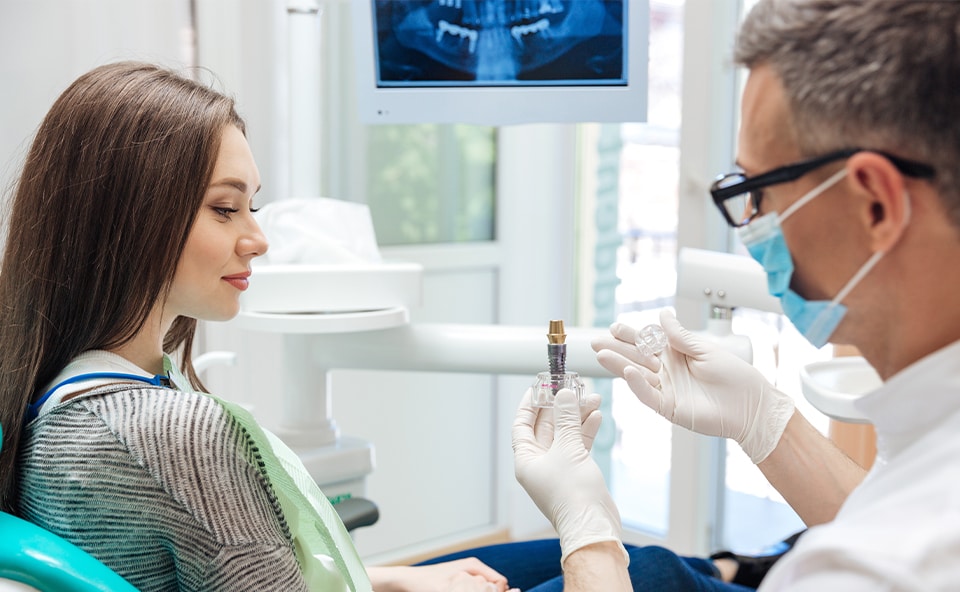 Lekarz tłumaczy pacjentowi wpływ higieny jamy ustnej na powodzenie leczenia implantologicznego.