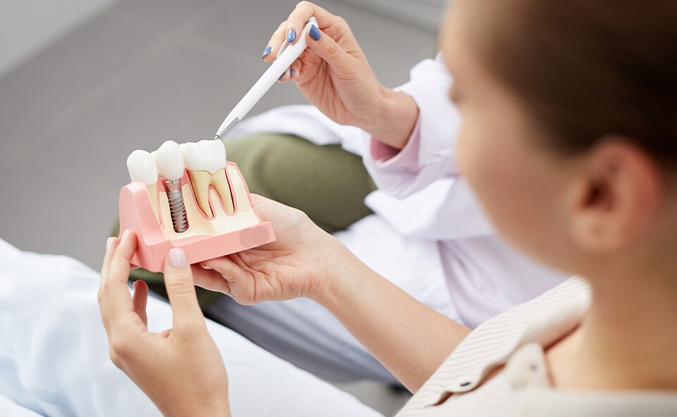 Higienistka stomatologiczna instruuje pacjenta, jak poprawnie dbać o higienę implantów zębowych.