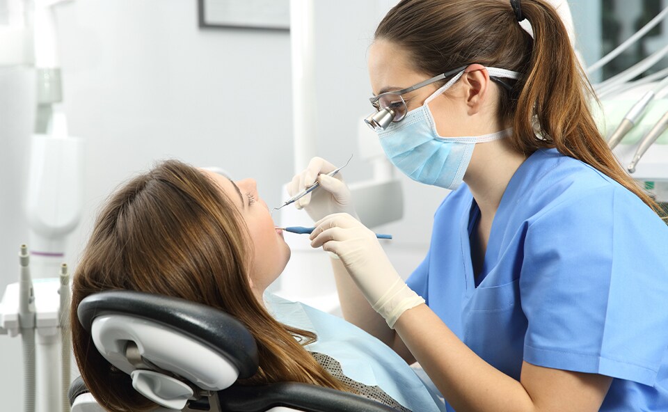 Higienistka stomatologiczna instruuje pacjenta implatologicznego odnośnie higieny jamy ustnej, przed zabiegiem higienizacji w gabinecie.