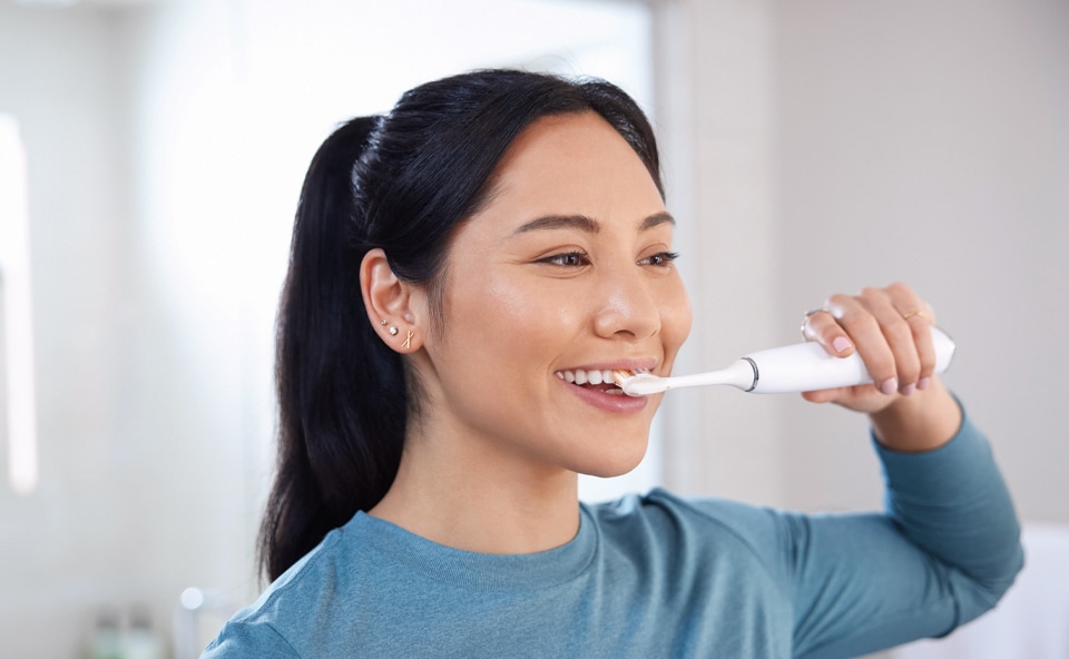Kobieta myjąca zęby szczoteczką soniczną Philips.