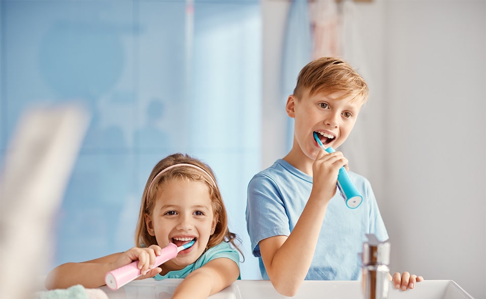 Dzieci myją zęby szczoteczką soniczną.