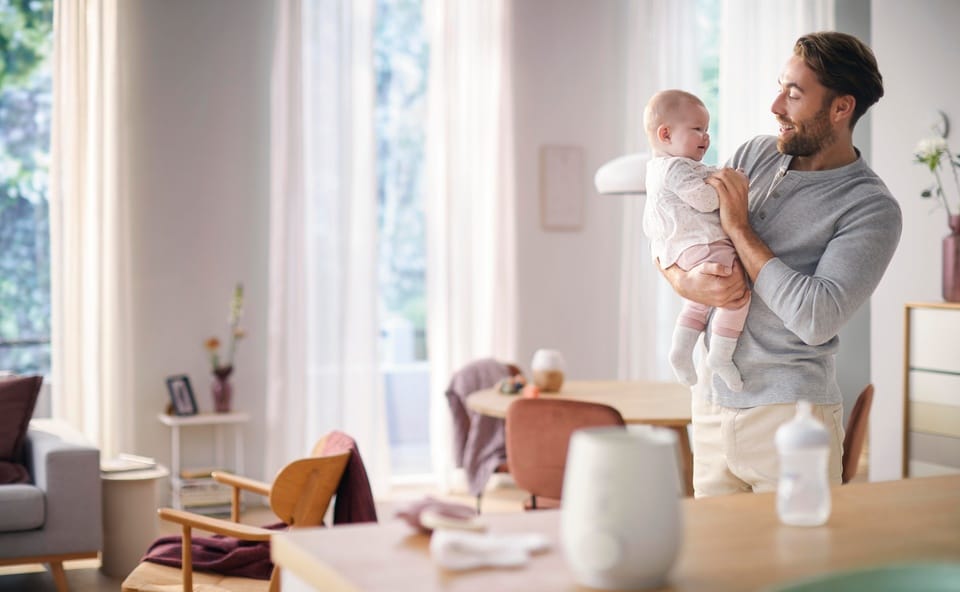 Tata z dzieckiem używający podgrzewacza do butelek Philips Avent