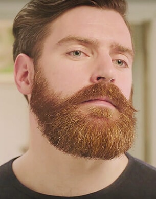 Mężczyzna przeglądający się w lustrze swojej brodzie oraz wąsom