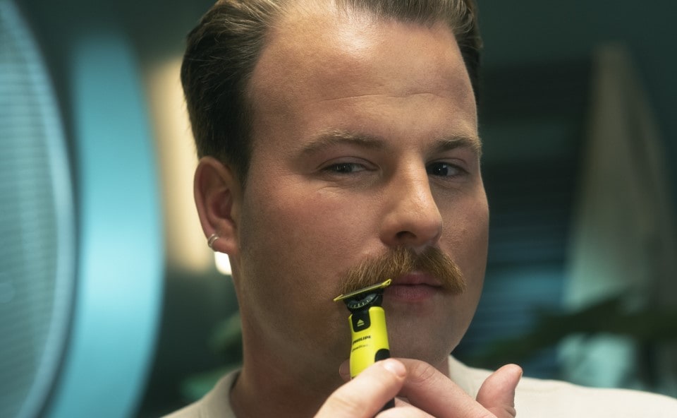 Mężczyzna modelujący swoje wąsy urządzeniem Philips.
