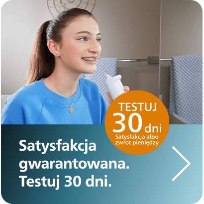 Grafika promująca 30-dniowy okres testowy irygatorów do zębów. Na obrazie znajduje się młoda kobieta z ciemnymi włosami, która używa białego irygatora do zębów. Tekst na grafice głosi: "Satysfakcja gwarantowana. Testuj 30 dni" oraz "Satysfakcja albo zwrot pieniędzy"