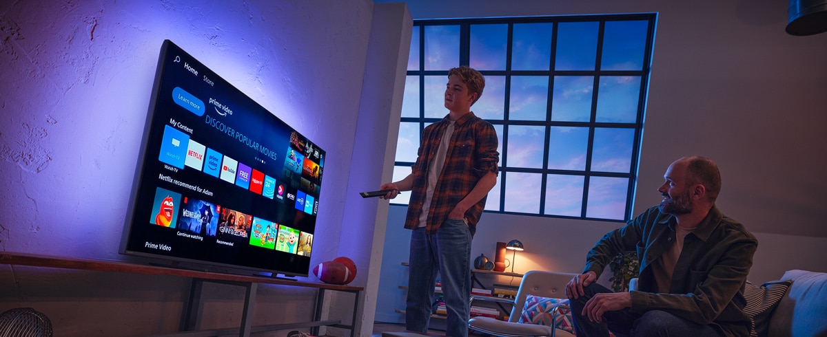 Mężczyzna wybierający aplikację na telewizorze Philips Smart TV